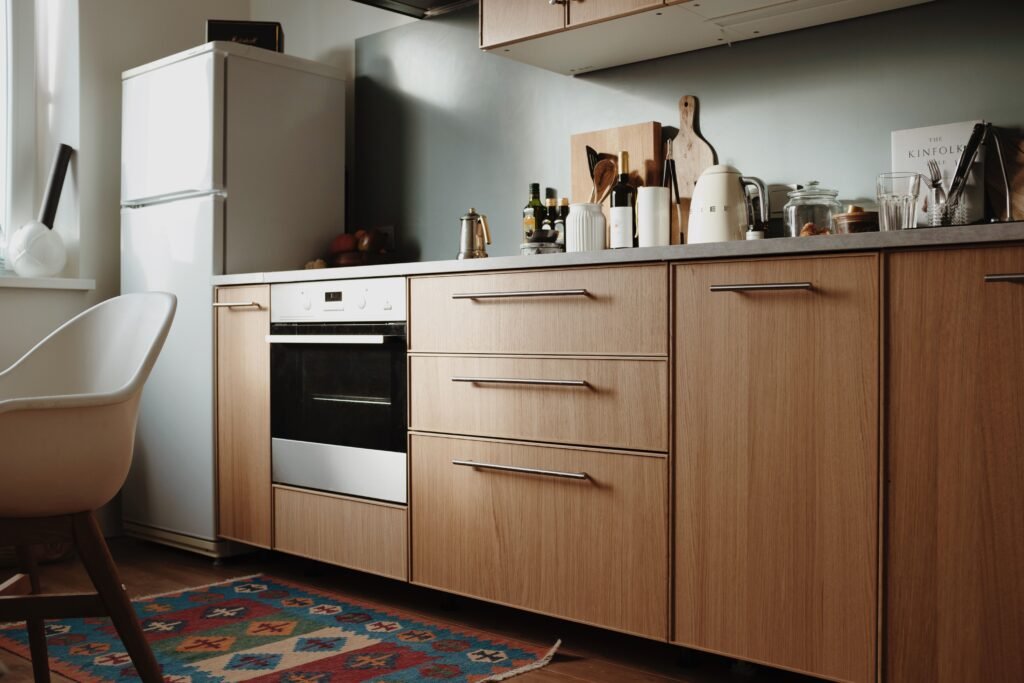 Scandinavian-style kitchen with freestanding white refrigerator, light wood cabinets, and built-in oven for appliance repair cibolo.