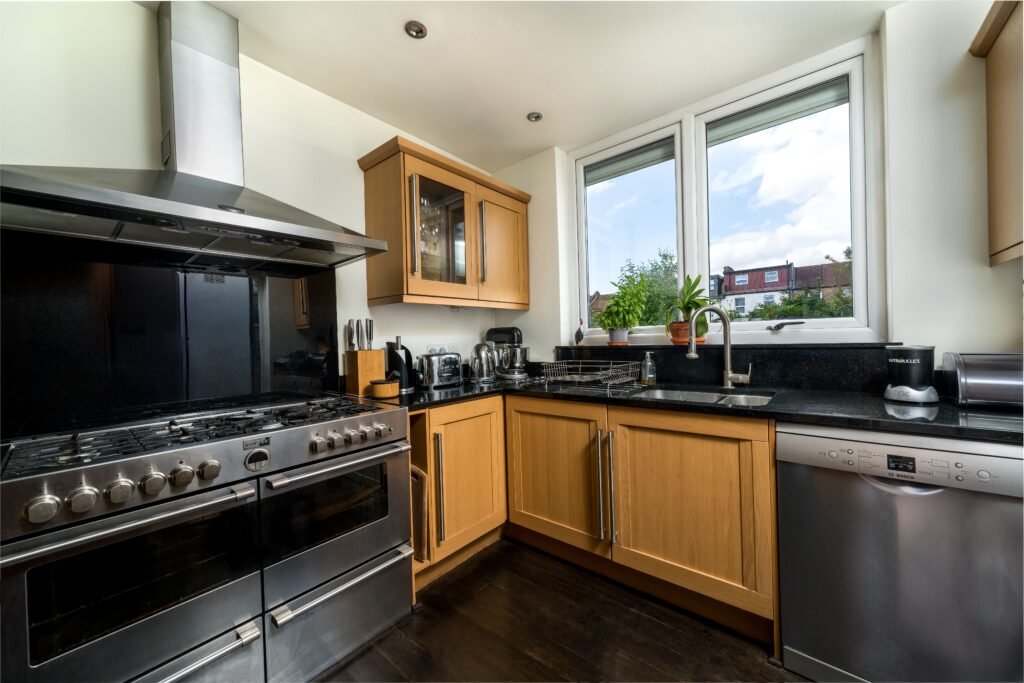 Warm traditional kitchen with stainless steel gas range, range hood, and wooden cabinets for appliance repair seguin.