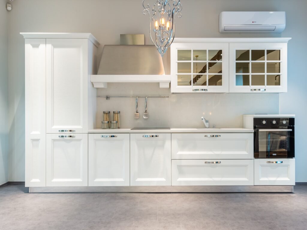 Bright white modern kitchen with stainless steel range hood, glass-front cabinets, and built-in wall oven for appliance repair seguin.